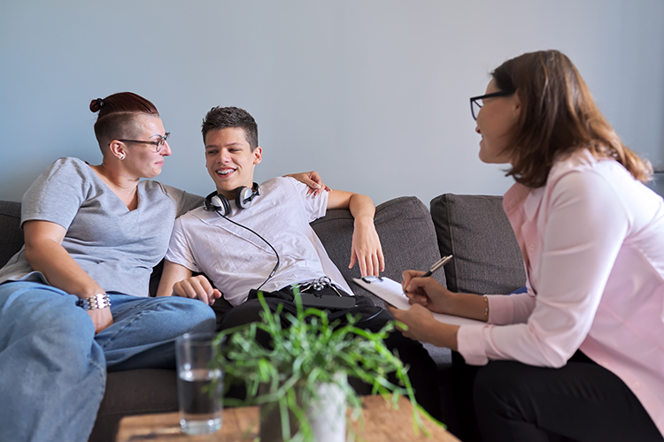 Mother with her teenage son at meeting with an allied health therapist discussing, mental health family, sitting on sofa