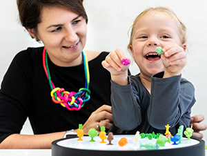 Toddler girl in child occupational therapy session doing sensory playful exercises with her occupational therapy assistant.