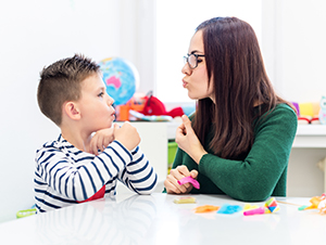 Allied health assistant speech therapy concept. Young boy with autism correct pronunciation with a female speech therapy assistant.