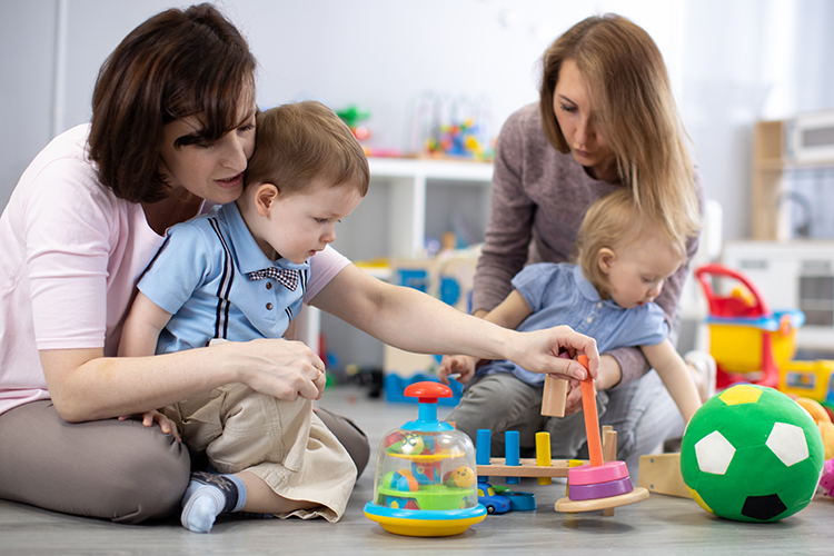 Allied health professional teaching allied health assistant to work with two young boys